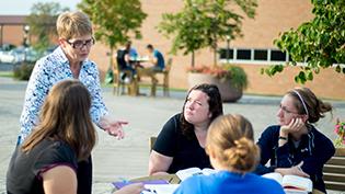 Professor talks to students at a table